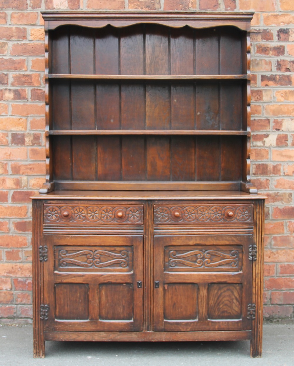 A 1920's oak dresser, with plate rack and two drawers, above two cupboard doors,