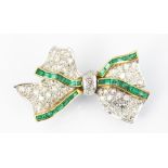 A diamond and emerald set bow brooch, designed as a pavé diamond set ribbon bow,