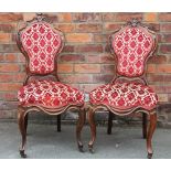 A set of four early Victorian carved rosewood dining chairs, with foliate red upholstery,