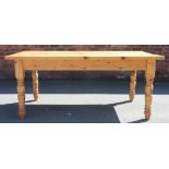 A pine farmhouse style kitchen table, with two drawers, on turned legs,