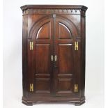A George III mahogany corner cabinet, with moulded cornice and two arched panelled doors,