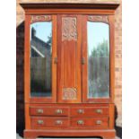 An Edwardian Art Nouveau walnut wardrobe, with two mirrored doors, over four short drawers,