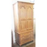 A pine wardrobe, with two doors over two short and two long drawers, on tuned legs,