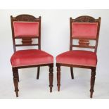 A set of four late Victorian carved walnut dining chairs, with red upholstered seats,