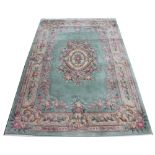 A modern Chinese wool carpet, worked with a floral design against a pale blue / green ground,