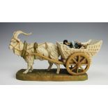 A Royal Dux porcelain model of a harnessed goat and cart, upon grassy base,