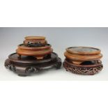 A selection of five Chinese carved and stained hardwood circular vase stands,