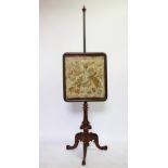 An early Victorian carved walnut and brass pole screen, with tapestry panel, on carved tripod base,