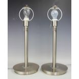 A contemporary pair of chromed metal lamps, each simplistically modelled upon a circular base,