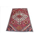 A Persian hand woven Hamadan wool rug, worked with a double red and cream medallion,