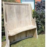 An 18th century provincial pine settle, possibly North Wales, of curved rustic form,