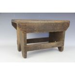 A rustic pine stool, with solid seat and standard end supports,