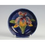 A Moorcroft Lily pattern dish, centrally decorated with a lily against a blue ground,