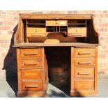 An Edwardian oak roll top desk, with fitted interior above six drawers, on plinth base,