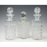 A pair of cut glass cylindrical decanters and stoppers, each with star cut bases, 26cm high,