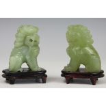 A pair of Chinese carved green hard stone models of temple dogs, on wood stands, in fitted box,