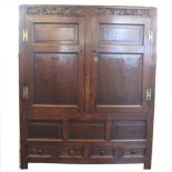 An 18th century oak livery cupboard, with carved detailing above two panelled doors,