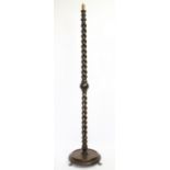 A 1920's oak standard lamp, with barley turned column, on circular base with brass paw feet,