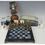 A modern marble chess board and brass chess pieces, with a pair of alabaster book ends, a cow bell,