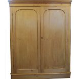 A Victorian pine wardrobe, with moulded cornice and two arched panelled doors, on plinth base,