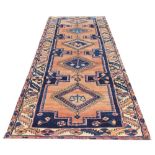 A Persian Heriz wool runner, worked with five medallions against a pale ground,