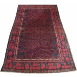 An Afghan Baluch wool tribal rug, worked with a foliate panel in red and blue,