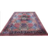 A large wool carpet, worked with a geometric patchwork design within floral borders,