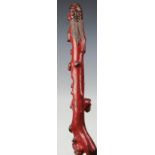 A Japanese red lacquered root wood walking stick, the handle carved with the head of a sage,