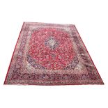 A large Kashan wool carpet, worked with an all over foliate design against a red and blue ground,