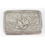 A silver brooch, the rounded rectangular brooch depicting a junk in full sail within beaded border,