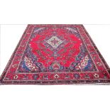 A large hand woven wool Persian Tabriz carpet, worked with floral sprays against a red ground,