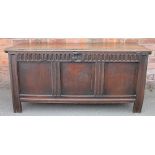 An 18th century oak coffer, the top with a chip carved edge, and panelled front, on stile legs,