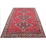 A hand woven wool Persian Shiraz rug, worked with three geometric gulls against a red ground,