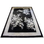 A Chinese rug, decorated with three floral sprays against a black ground, 244cm,