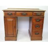 An Edwardian oak pedestal desk, with six drawers and a cupboard door,