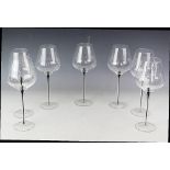 A set of seven black stemmed large red wine glasses,