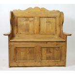 A Victorian style pine box seat settle, of small proportions, with serpentine top, on panelled base,