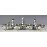 An assembled seven piece silver condiment set comprising; four silver cauldron shaped salts,