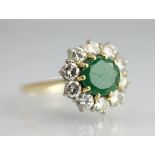 An emerald and diamond circular cluster ring, the central circular emerald,