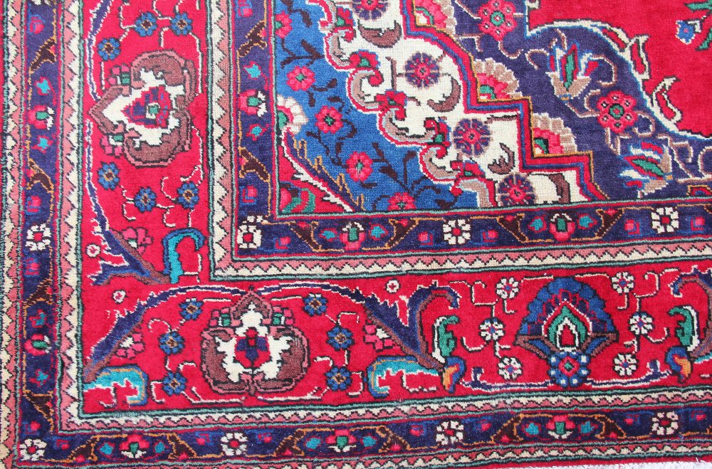 A large hand woven wool Persian Tabriz carpet, worked with floral sprays against a red ground, - Image 2 of 2