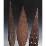 Three carved wood tribal paddles along with a similar smaller example,