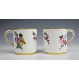 A pair of French porcelain coffee cups, each florally painted and within gilt decorated rims,