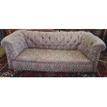 A late Victorian Chesterfield settee, with button back upholstery, on oak legs,