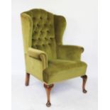 A 1920's stained beech wing back arm chair, with green upholstery, on cabriole legs,