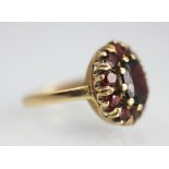 A garnet set cluster ring, the central oval garnet within a surround of ten further garnets,