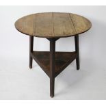 An 18th century oak cricket table, with circular top above an under tier, on triangular legs,