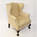 A George II style carved walnut wing back arm chair, late 19th century, with beige upholstery,