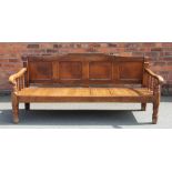 A late George III oak settle, with four panelled back above a solid seat, on turned legs,