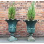 A pair of green painted cast iron garden urns, with flared and shaped rims,