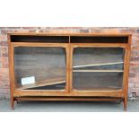 A bespoke crafted walnut low bookcase, with two glazed doors and ribbed side panels,